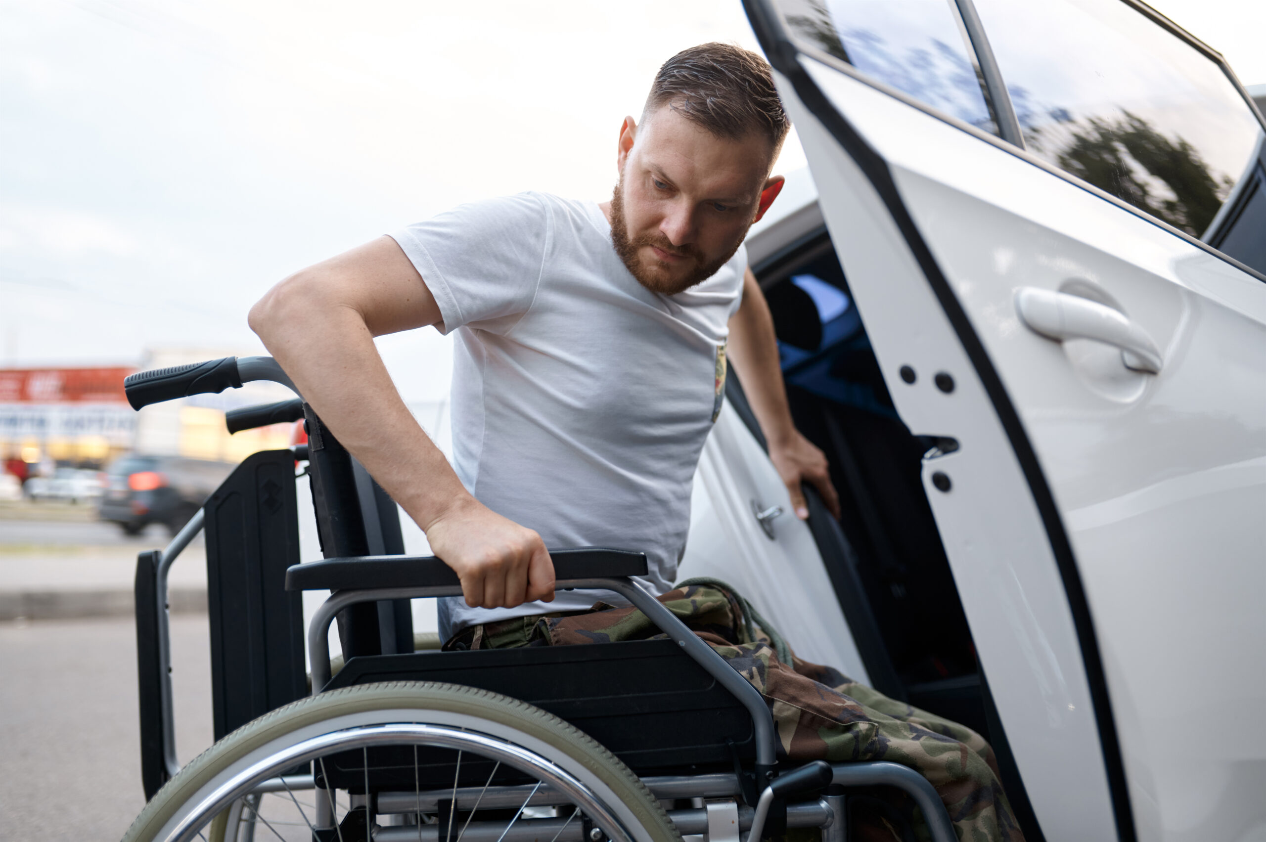 Retired veteran independently transfers from a car to a wheelchair. Paralyzed people and disability, handicap overcoming. Disabled male person